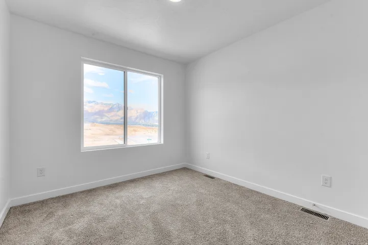 White walls, neutral carpet, and a large window framing a mountain backdrop