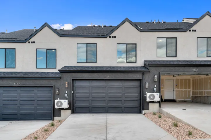 Contemporary exterior with multiple garage bays, dark framed windows, and a paved driveway