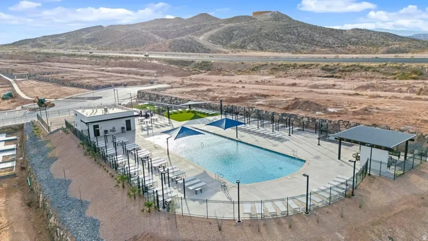 Expansive community pool area featuring an in-ground swimming pool, shaded lounge seating, and a dedicated pool house