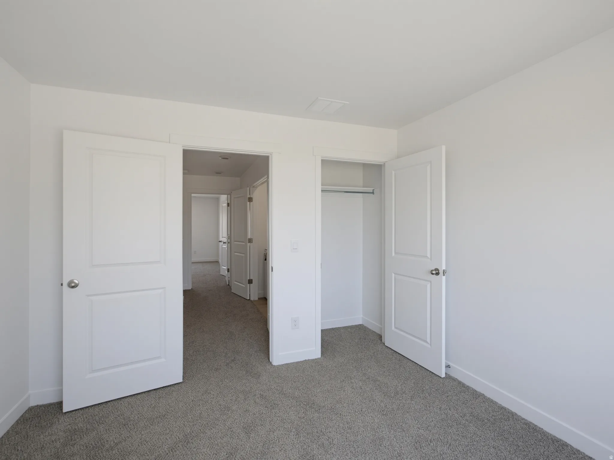 Neutral-toned carpeting, white interior doors, and a built-in closet with hanging rod