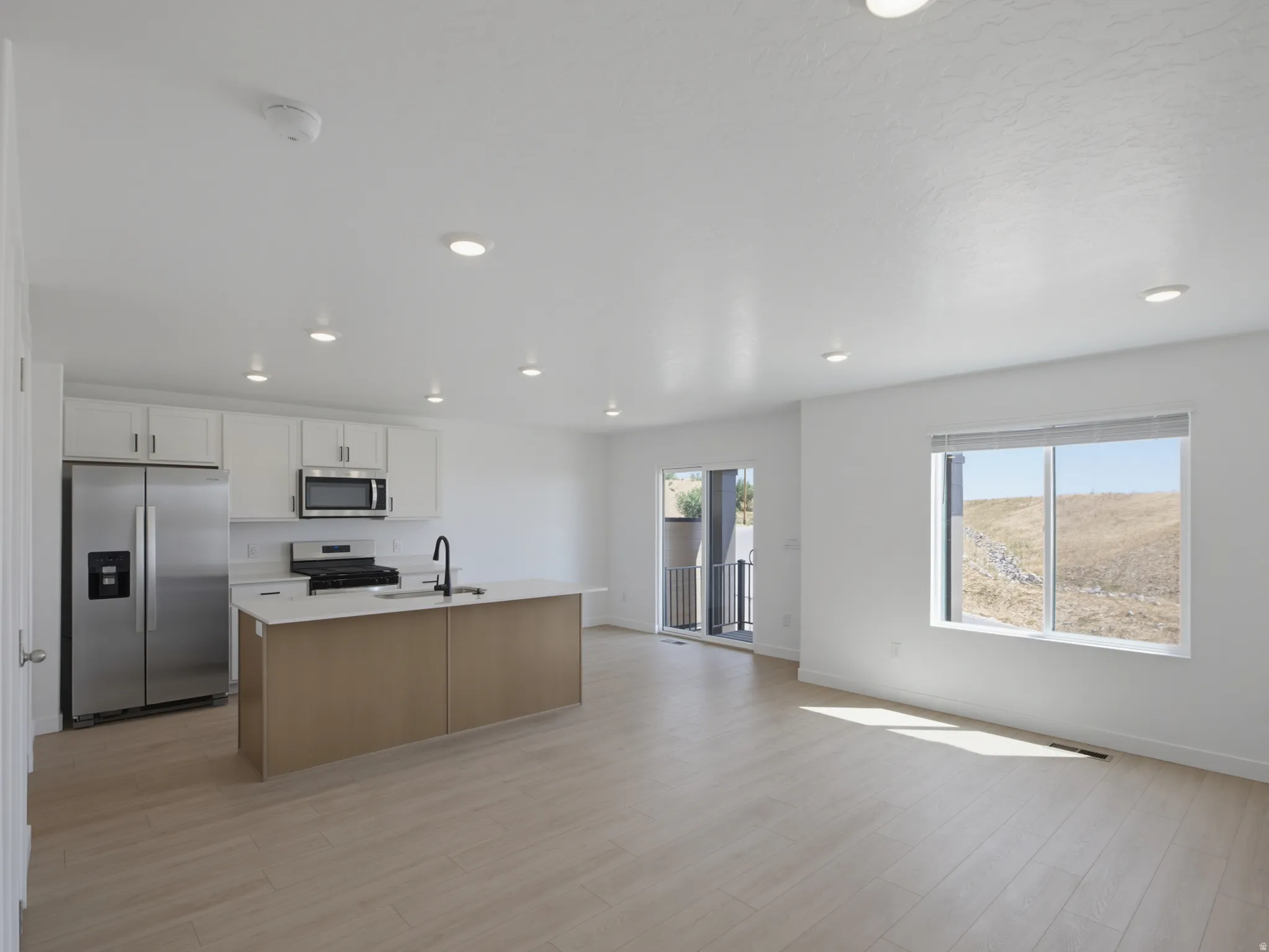 Open-concept living space with recessed lighting, wood-finish flooring, and a sliding glass door