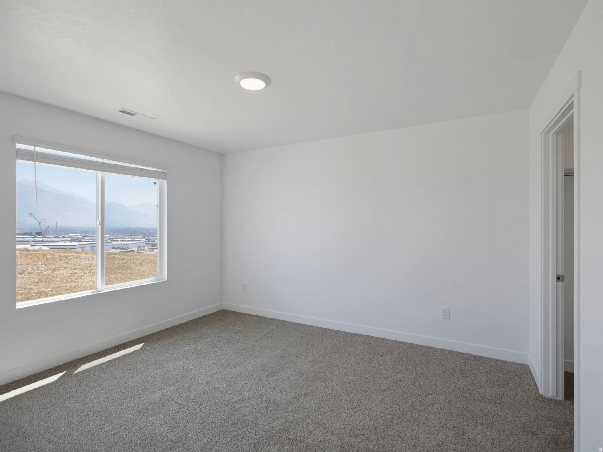 Carpeted flooring, white walls, and a window with mountain scenery