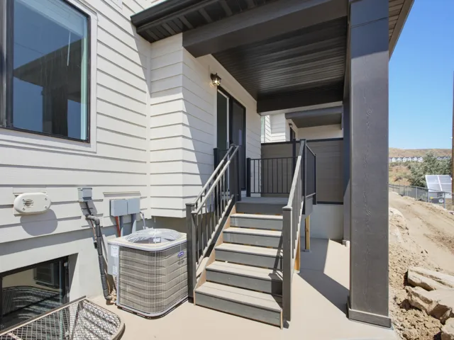 Covered patio featuring composite decking stairs, black metal railings, and a sliding glass door entry