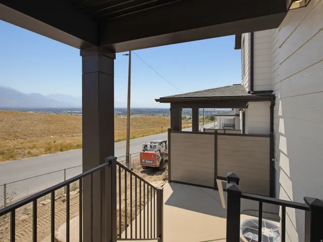 Exterior siding, dark trim, black metal railing, concrete patio, and privacy screening