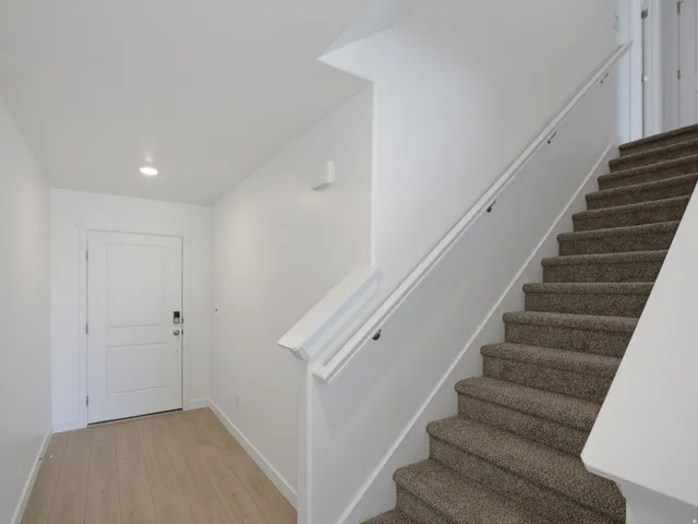 Staircase featuring a carpeted runner and white handrail