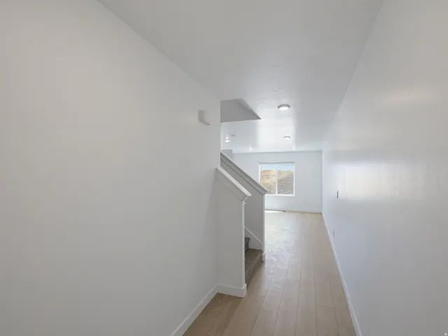 Hallway featuring wood-finish flooring, recessed lighting, and a carpeted staircase with white railings