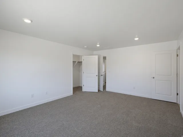 Recessed lighting, neutral gray carpeting, white walls, and white trim