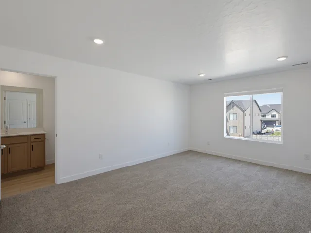 Expansive carpeted room with recessed lighting and a large window