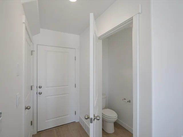 White interior doors with panel detailing, light wood-finish flooring, and white walls