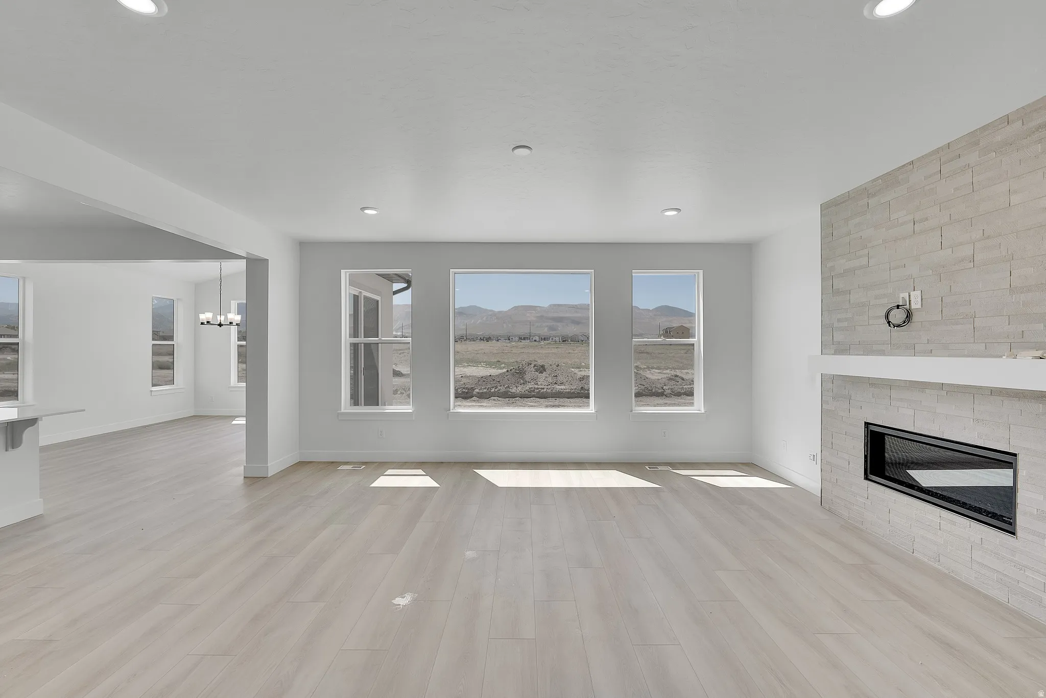 Recessed lighting, wood-finish flooring, multiple windows, built-in fireplace, and a stone tile fireplace surround