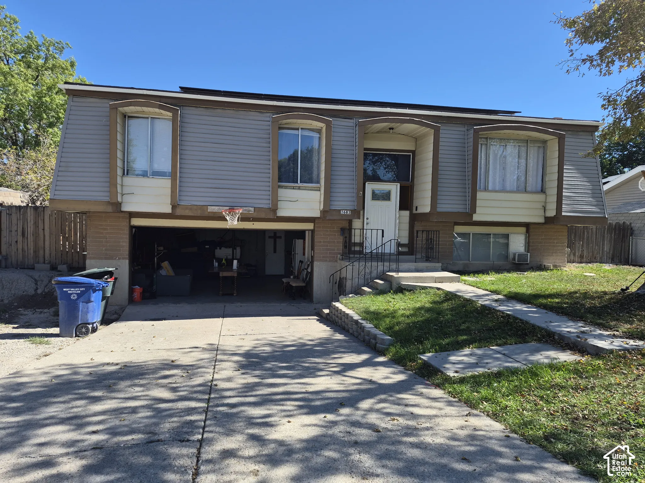Split-level residence featuring a two-car garage, concrete driveway, and a front entry with metal railings