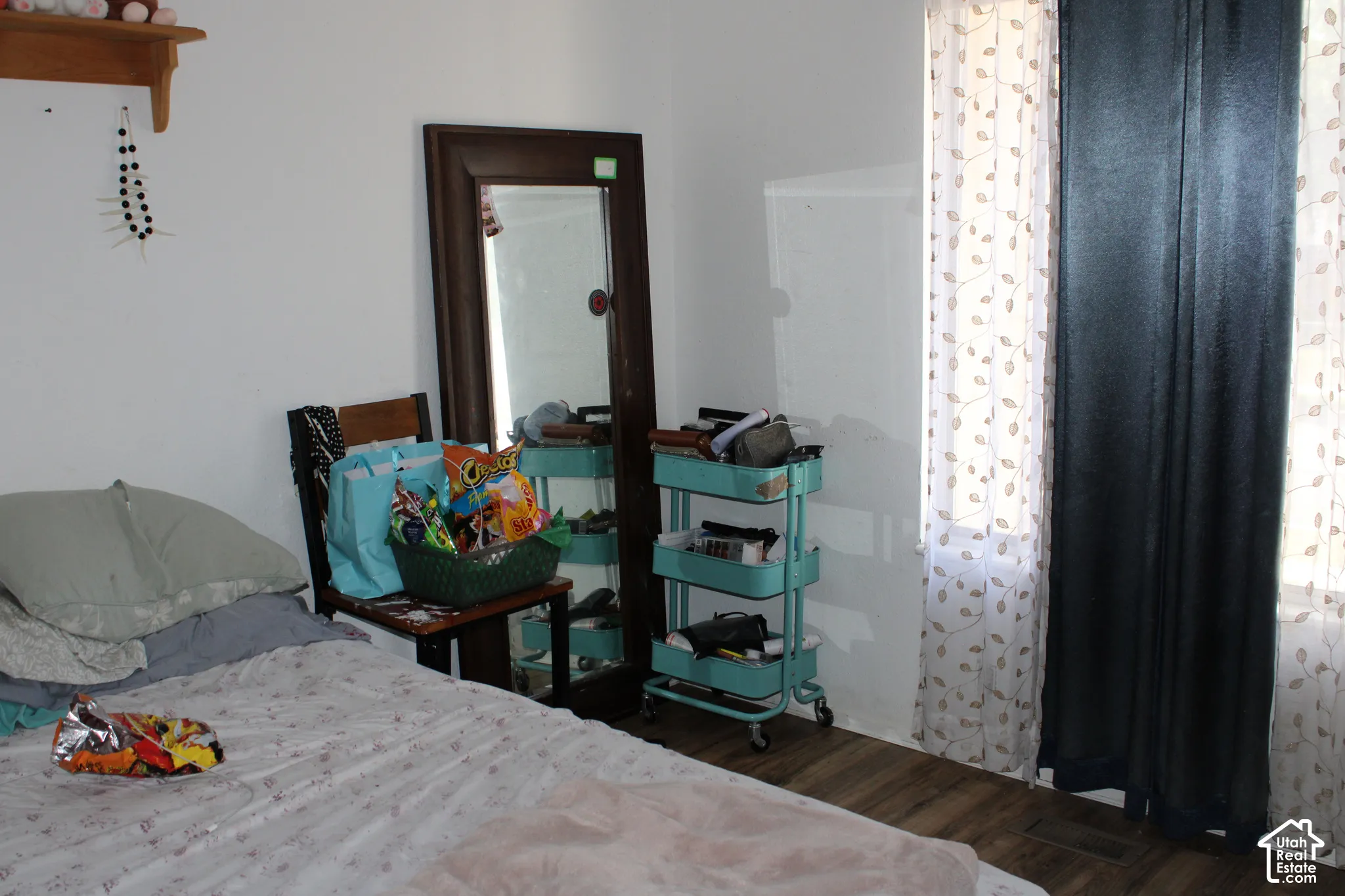 Wood-finish flooring, white walls, and a window with sheer and solid privacy coverings