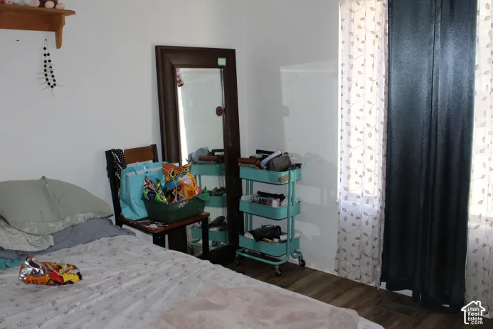 Wood-finish flooring, white walls, and a window with sheer and solid privacy coverings