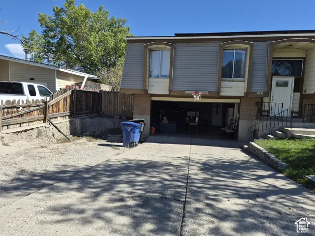 Multi-level exterior with a concrete driveway, attached garage, and a white entry door