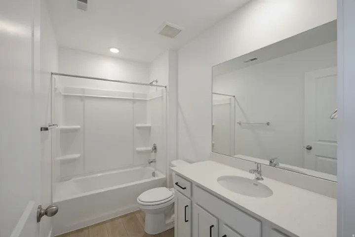 White vanity with a single basin sink, chrome faucet, and expansive mirror