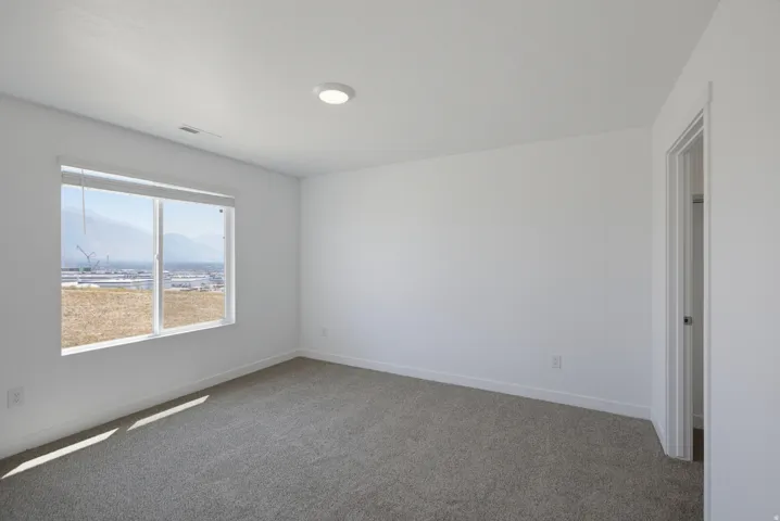 Recessed ceiling lighting, neutral carpet flooring, white walls, and a white-trimmed window with a mountain backdrop
