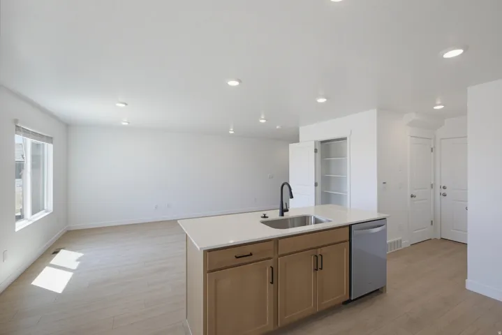 Open-concept living area featuring wood-finish flooring, recessed lighting, and an island with an integrated sink and dishwasher