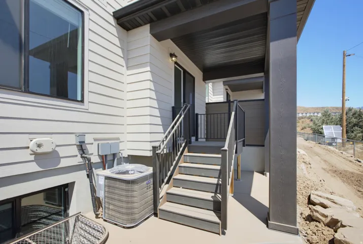 Exterior deck with steps featuring dark wood-finish railing and support beams