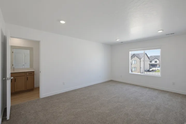 Expansive carpeted room with recessed lighting and a large window