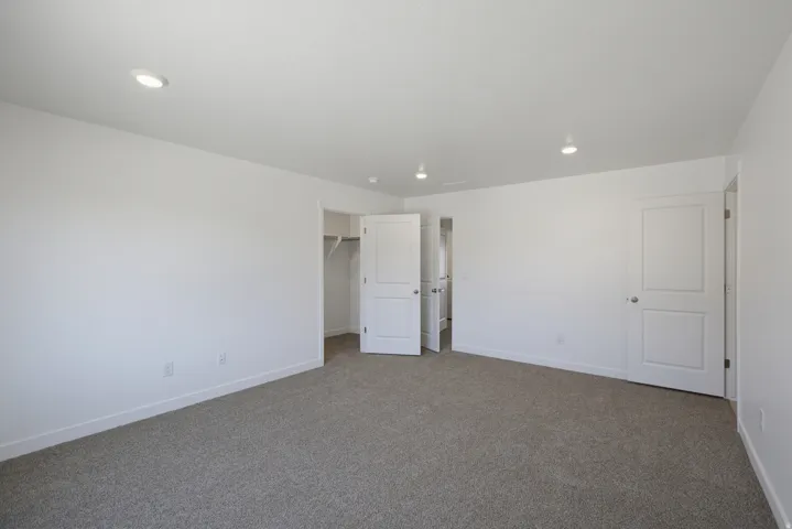 Recessed ceiling lighting, white interior doors, neutral paint, and carpet flooring