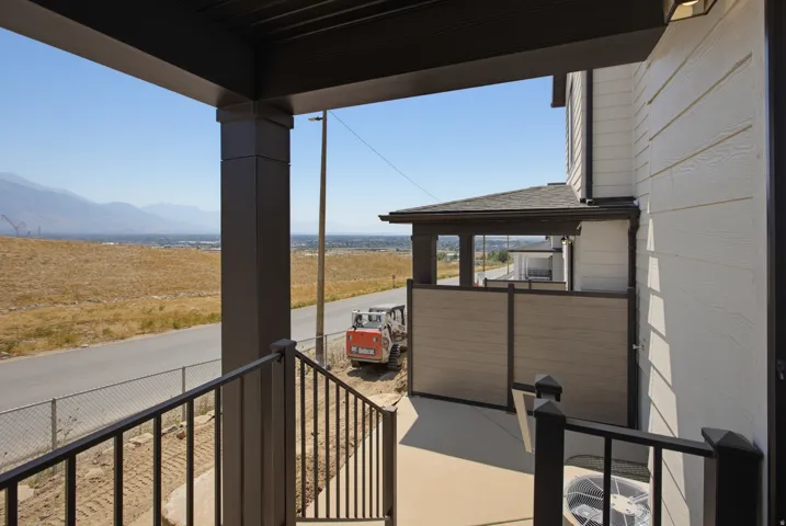 Covered outdoor patio with a concrete surface, black metal railings, and a privacy wall