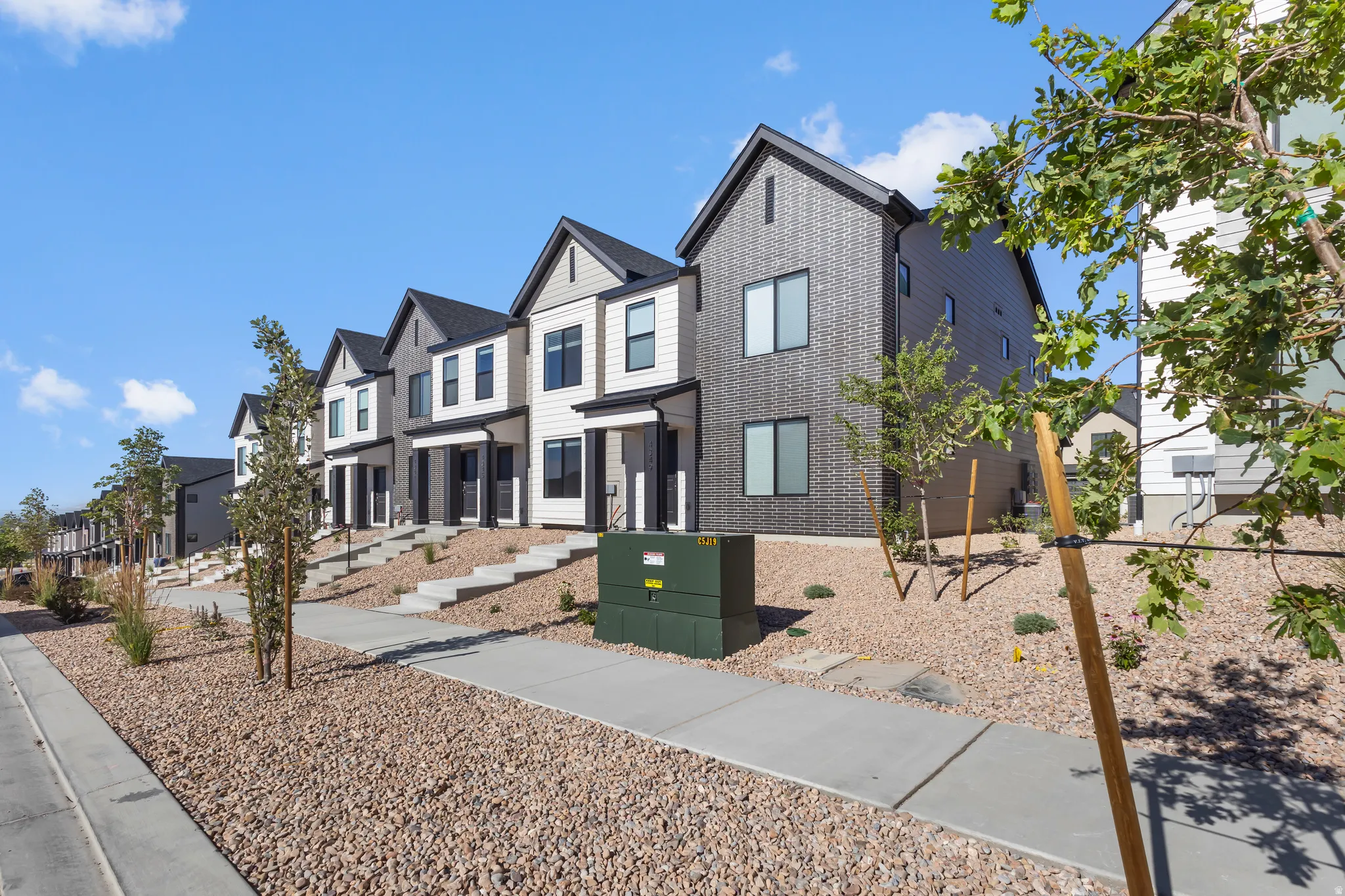 Contemporary townhomes featuring varied dark and light siding, prominent gables, and individual entryways