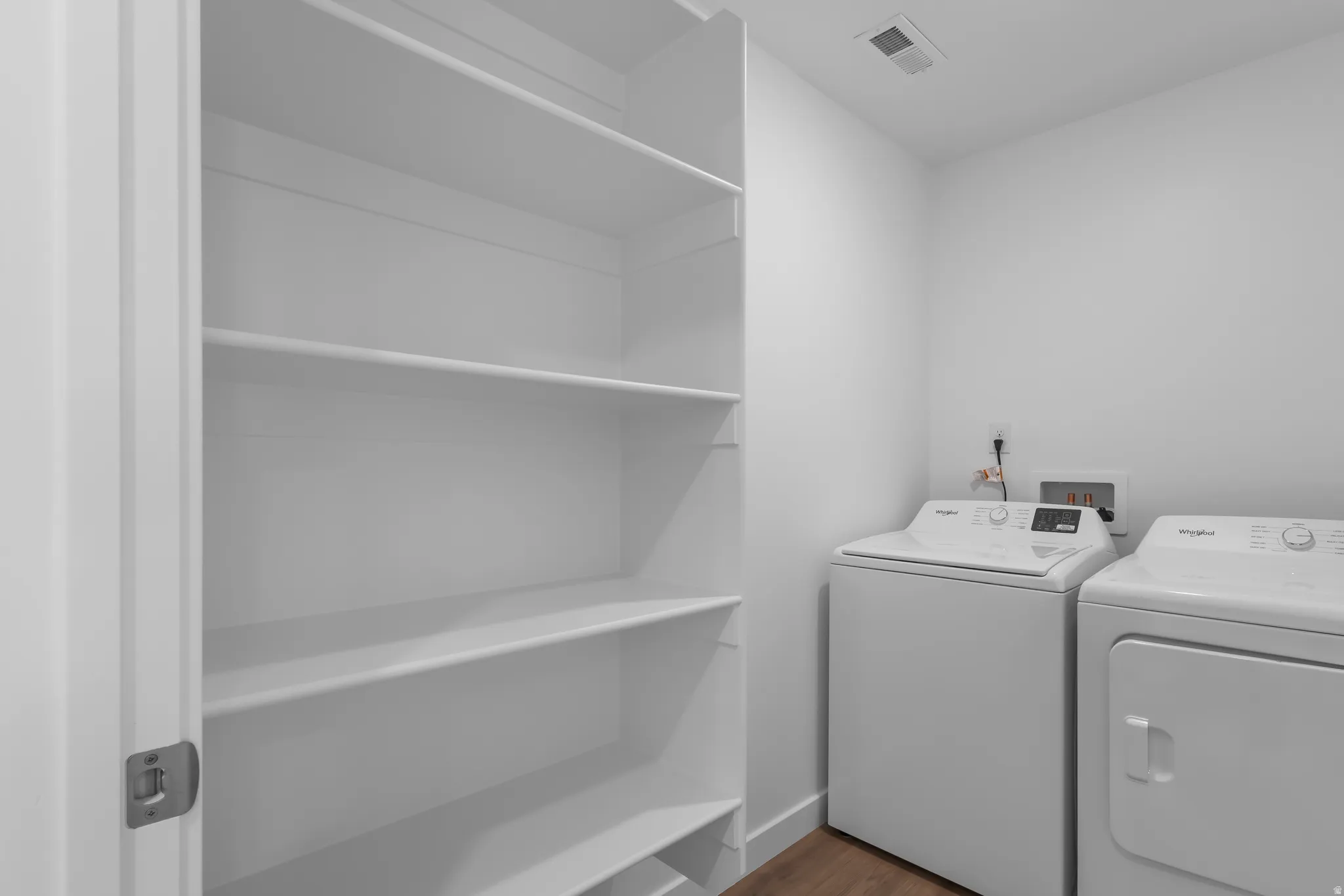 Laundry area with built-in shelving and wood-finish flooring