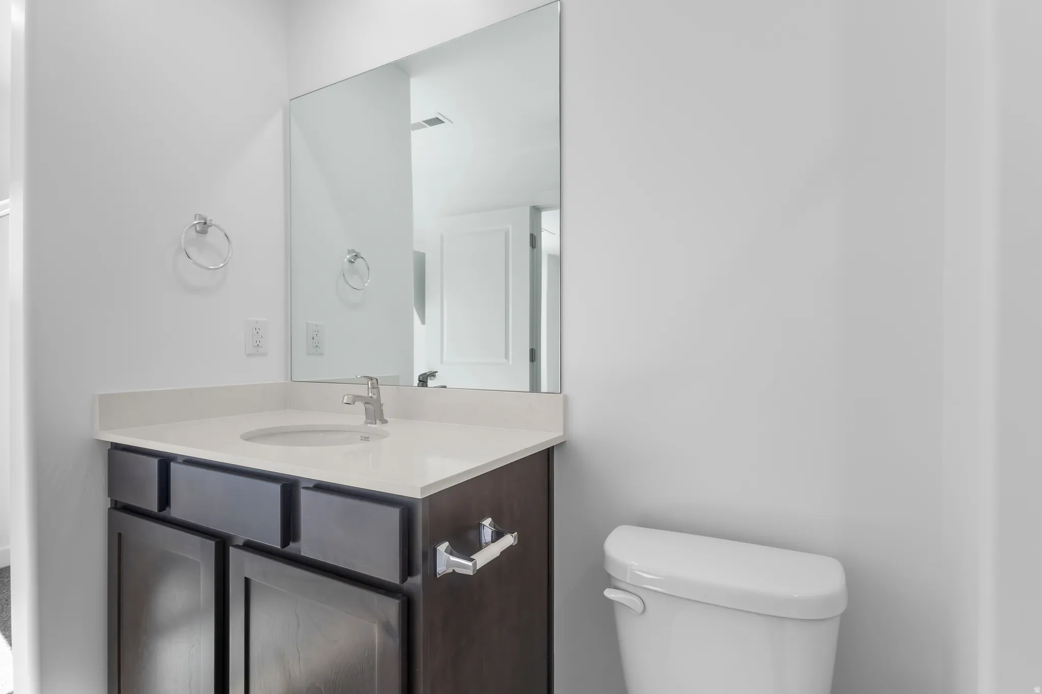 Vanity with an integrated sink, polished chrome faucet, and expansive wall-mounted mirror