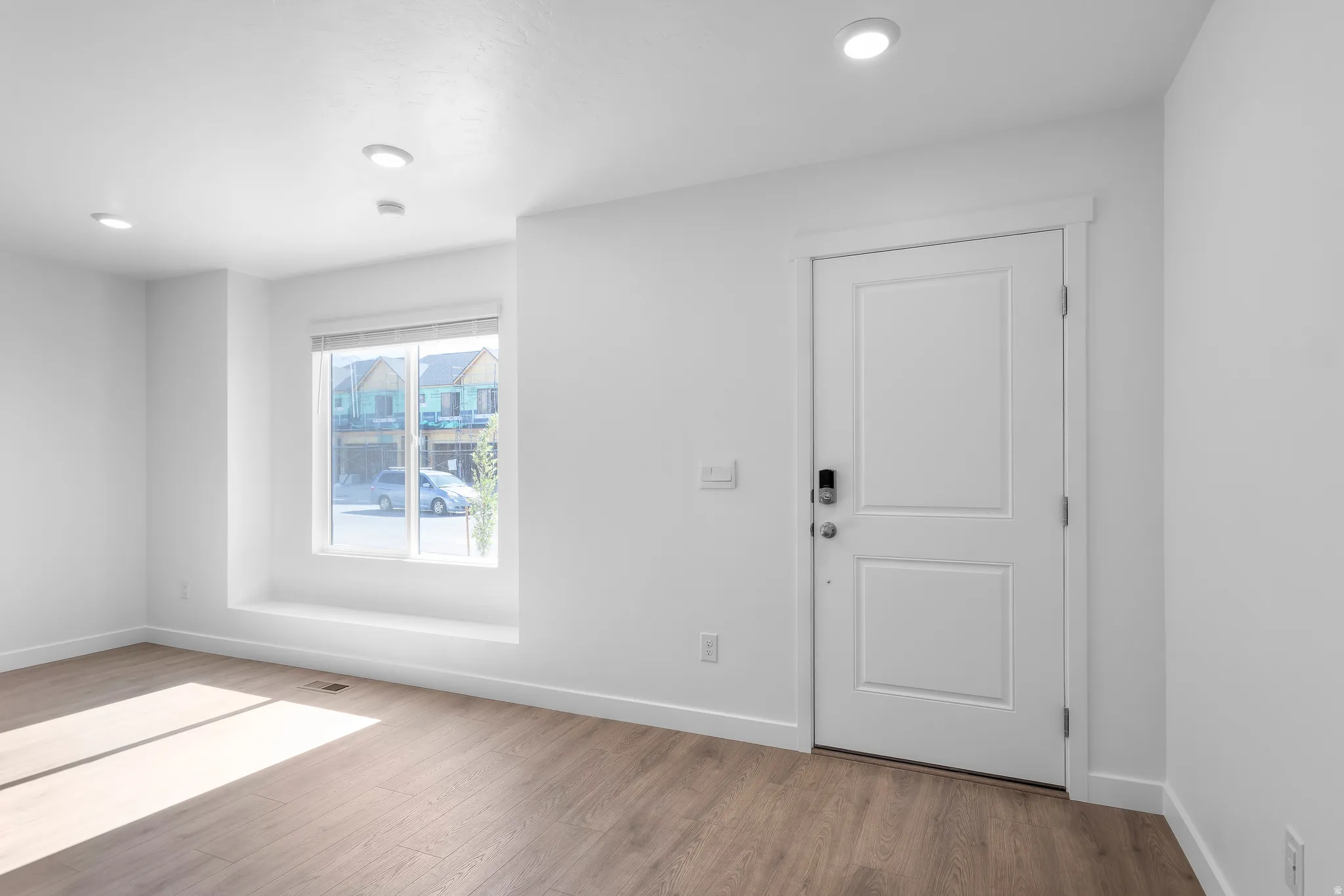 Recessed lighting, wood-finish flooring, white trim, and a window with a built-in ledge