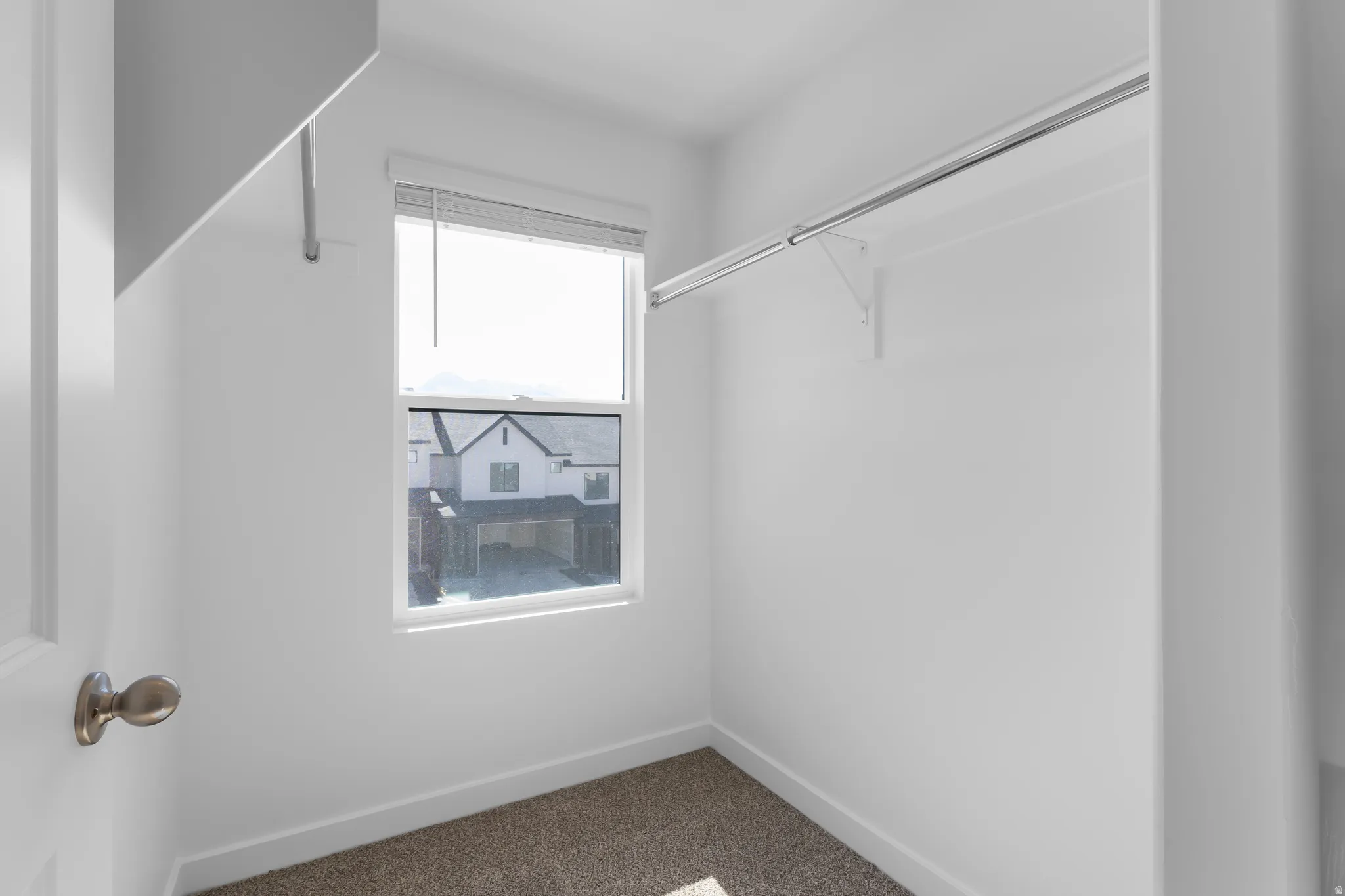 Recessed window with blinds, white painted walls, and neutral carpeting