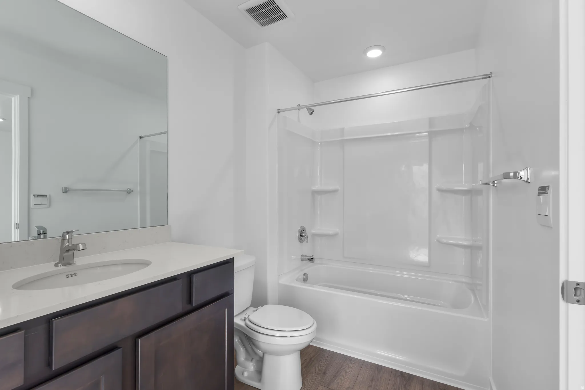 Bathroom featuring a dark wood-finish vanity with a light countertop, an undermount sink, and a mirrored wall