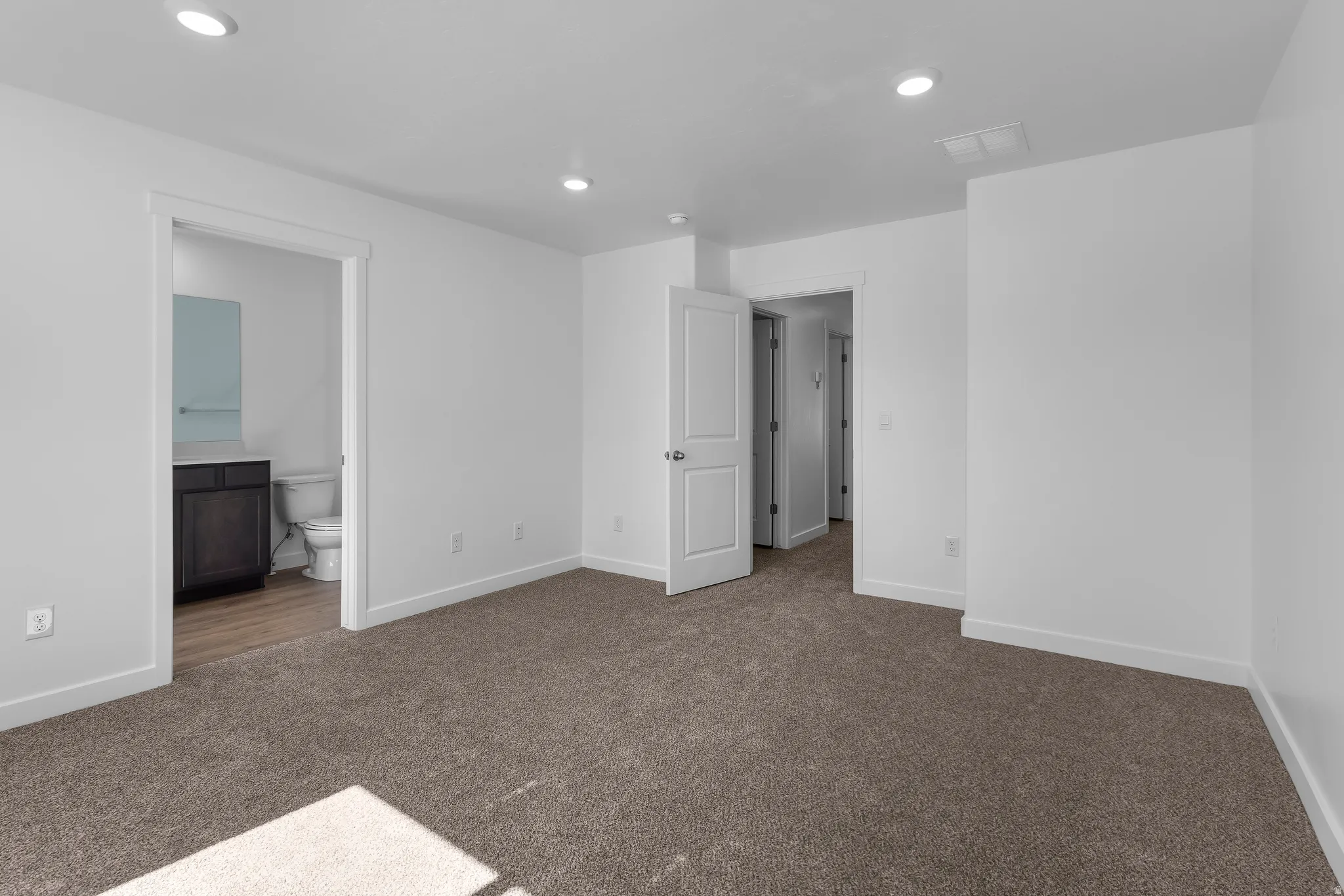 Plush carpeting, recessed lighting, and bright white walls
