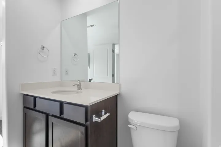 Vanity with an integrated sink, polished chrome faucet, and expansive wall-mounted mirror