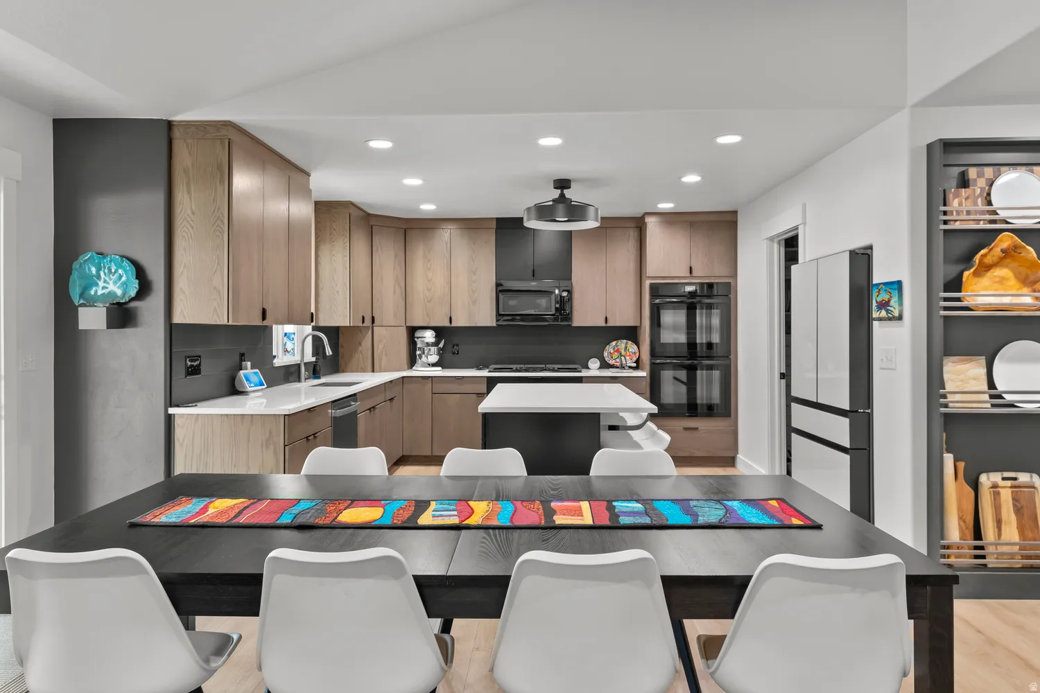 Modern kitchen featuring light wood-finish cabinetry, white countertops, built-in double ovens, and recessed lighting