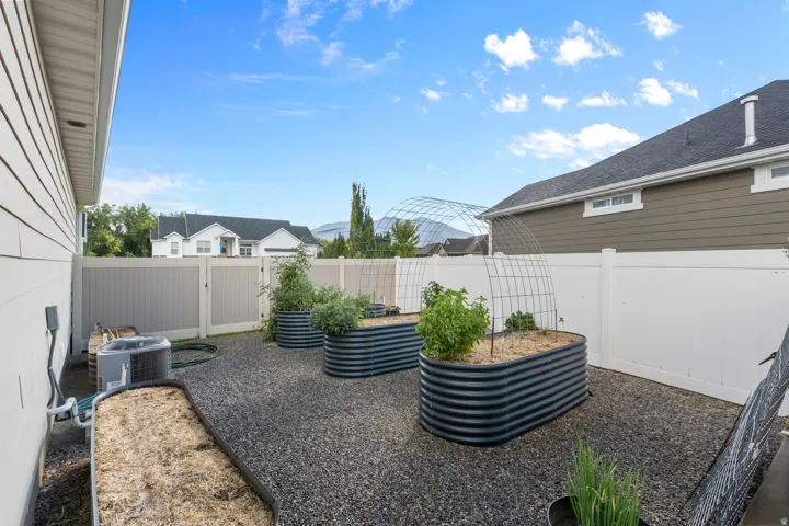 Landscaped backyard featuring multiple raised garden beds, gravel ground cover, and full perimeter fencing