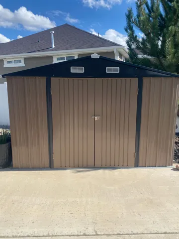 Outdoor storage shed with dual front doors and a sloped roof, one of 2 sheds besides huge shop