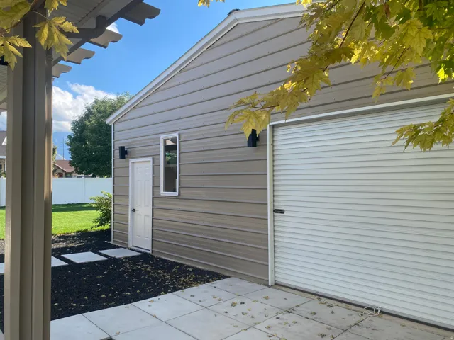 Siding exterior featuring a roll-up garage door, an exterior door, deluxe shop