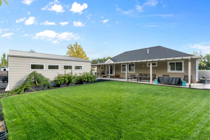 Expansive lawn, covered patio, separate outbuilding with multiple windows, and mature landscaping, mulitple berries