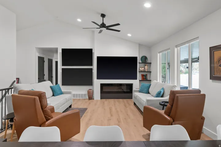 Vaulted ceiling with recessed lighting and ceiling fan, wood-finish flooring, and a built-in fireplace