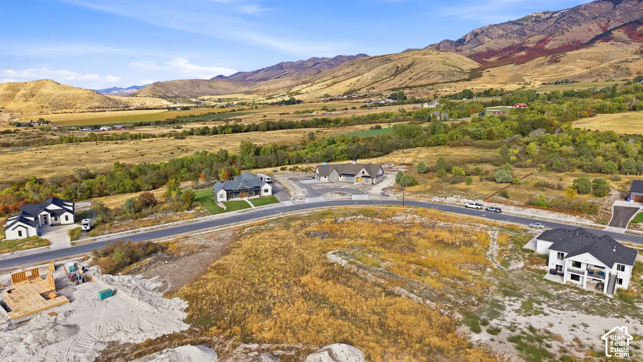 Expansive undeveloped land with a paved road, surrounded by natural terrain and distant mountains