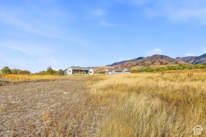 Ranch-style dwelling with a covered front porch, stone accents, and a gabled roofline, set against a mountain backdrop