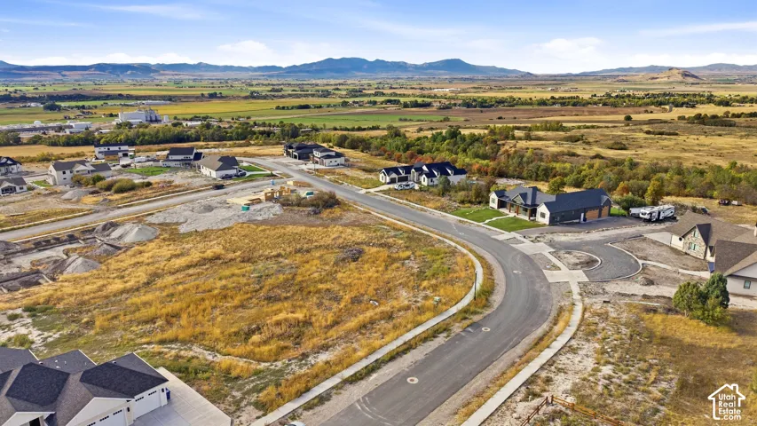 Expansive rural landscape with distant mountains, featuring a developed residential street and building lots
