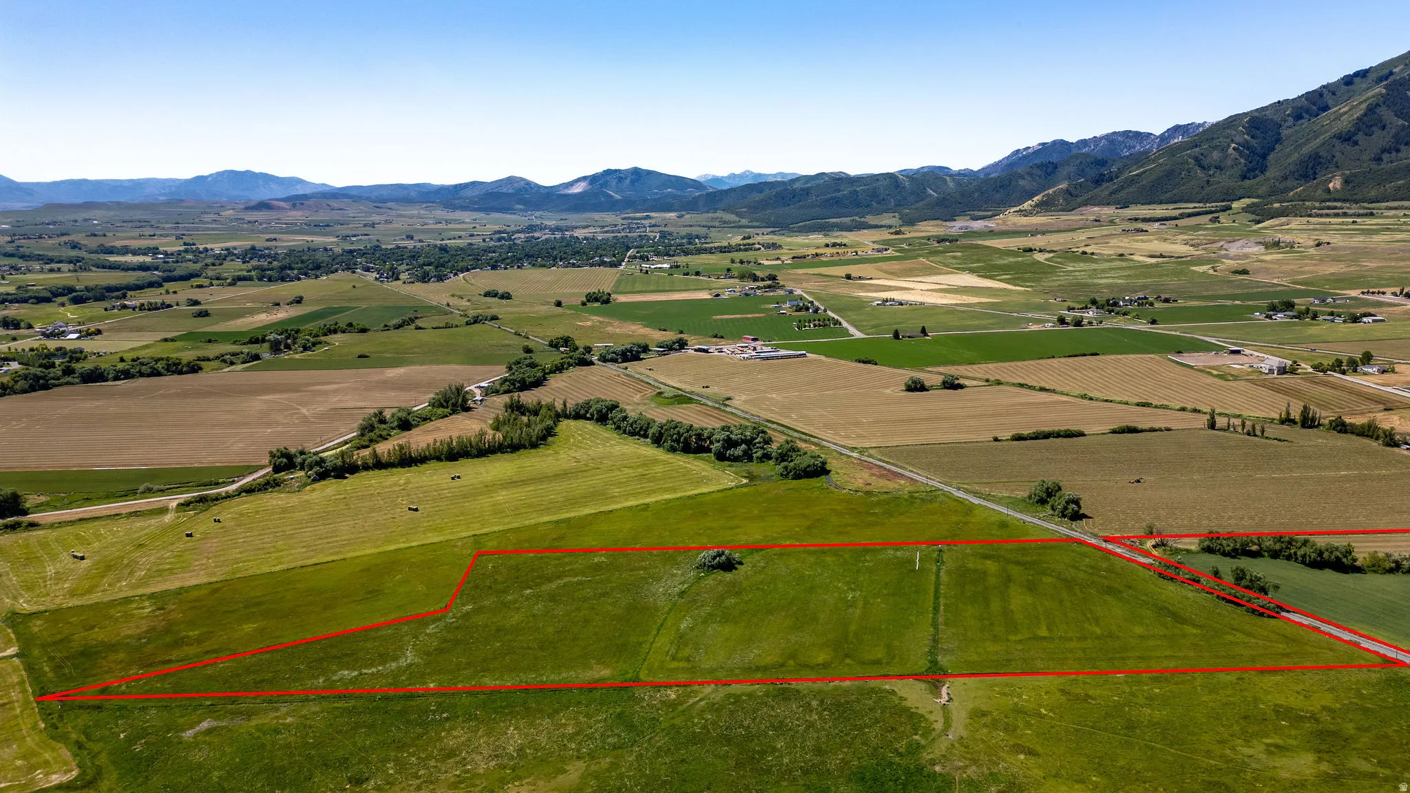 Expansive agricultural acreage with defined property lines, surrounded by open fields, and framed by distant mountain ranges