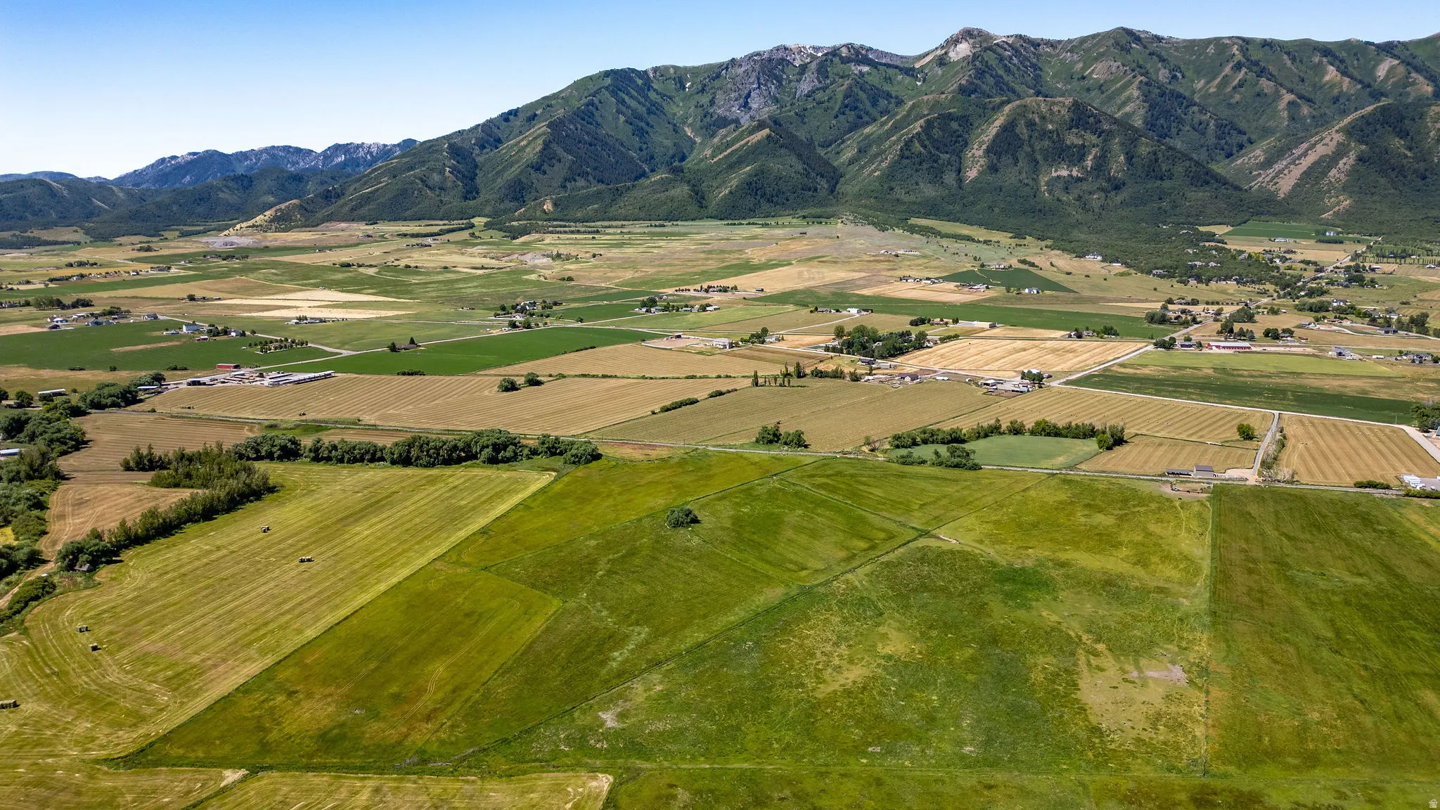 Expansive open fields with varied agricultural plots and distant mountain ranges