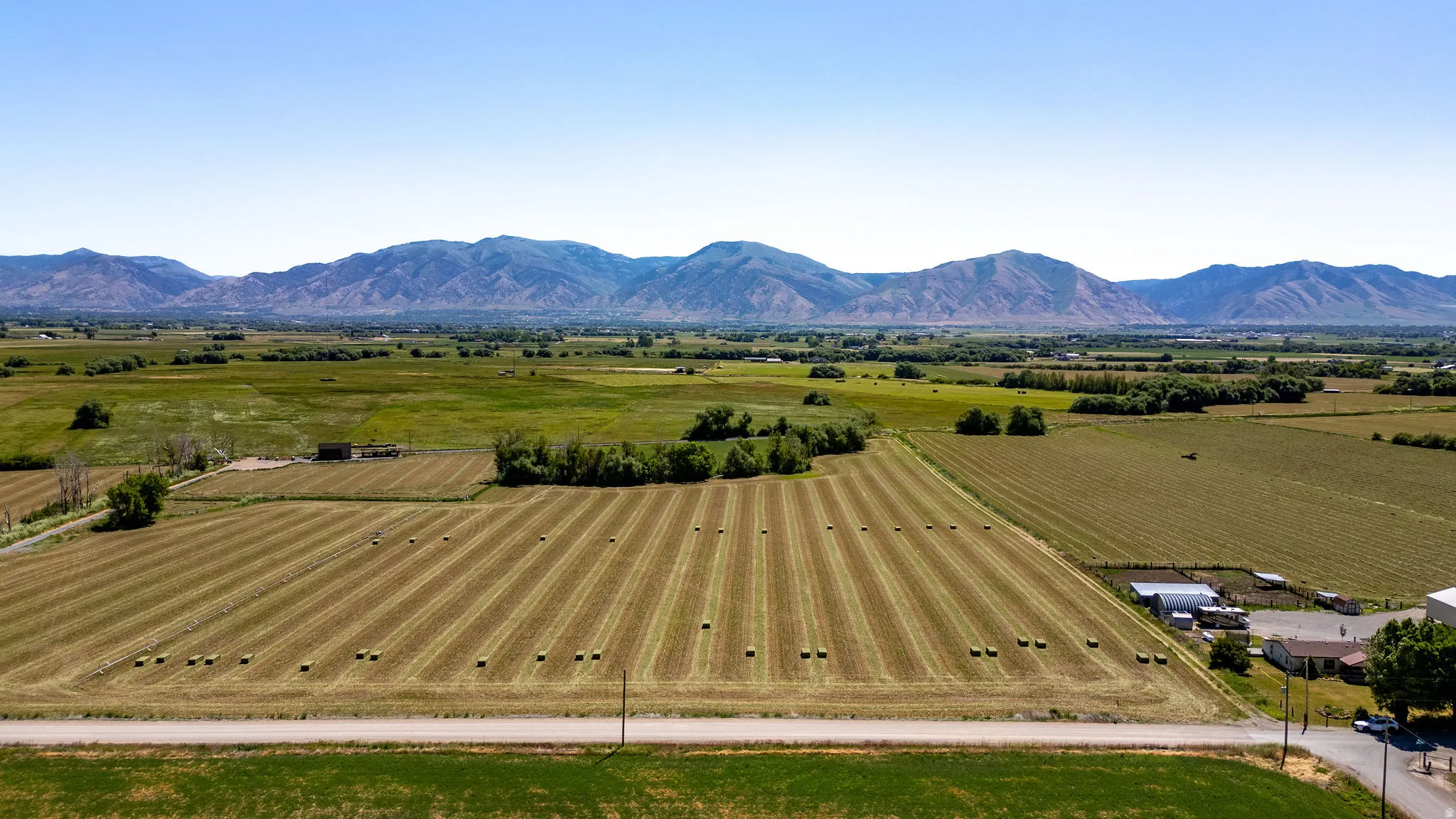 Expansive fields with agricultural patterns, distant mountain range, and scattered rural structures