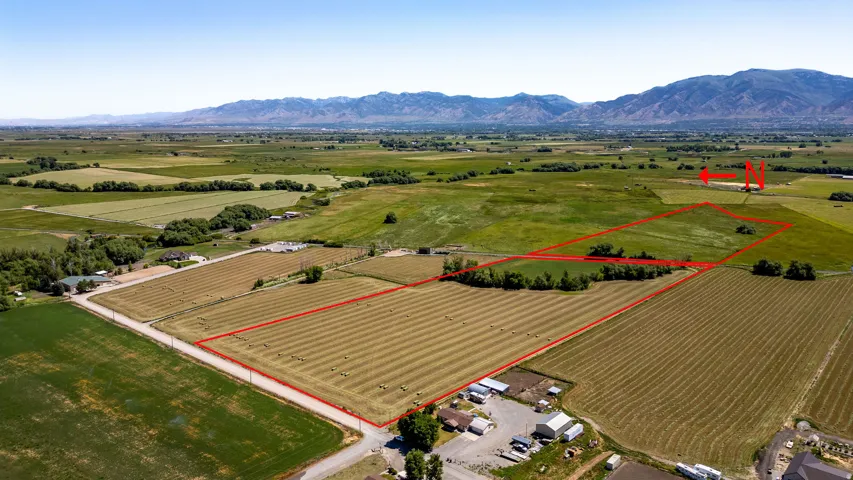 Expansive agricultural land featuring cultivated fields, open green spaces, and a mountainous backdrop