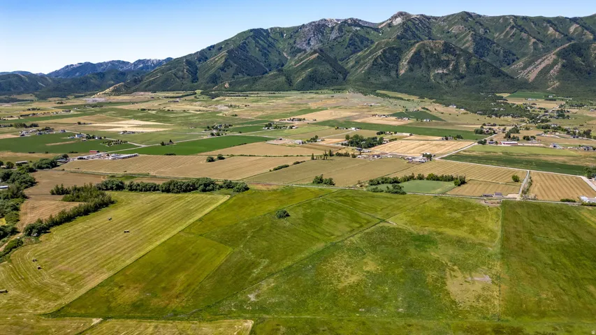Expansive open fields with varied agricultural plots and distant mountain ranges