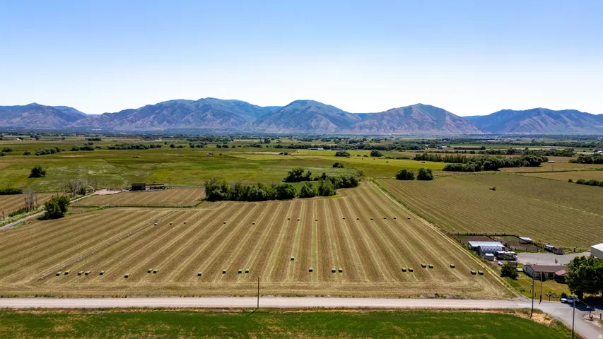 Expansive fields with agricultural patterns, distant mountain range, and scattered rural structures