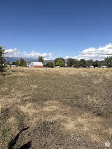 Expansive lot featuring a natural ground cover, distant mountains, and a clear sky backdrop