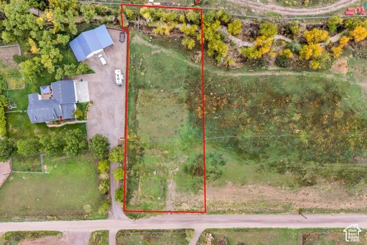 Expansive parcel featuring a large detached residence, a separate auxiliary structure with a blue roof, and a gravel driveway